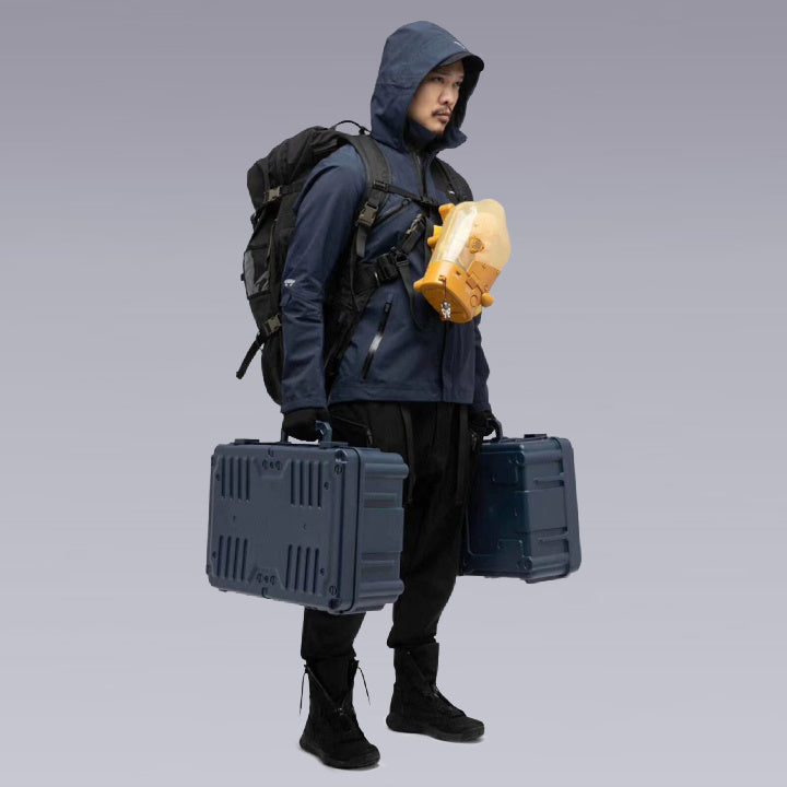 A man wearing the Death Stranding techwear Jacket, and a backpack holding two suitcases 