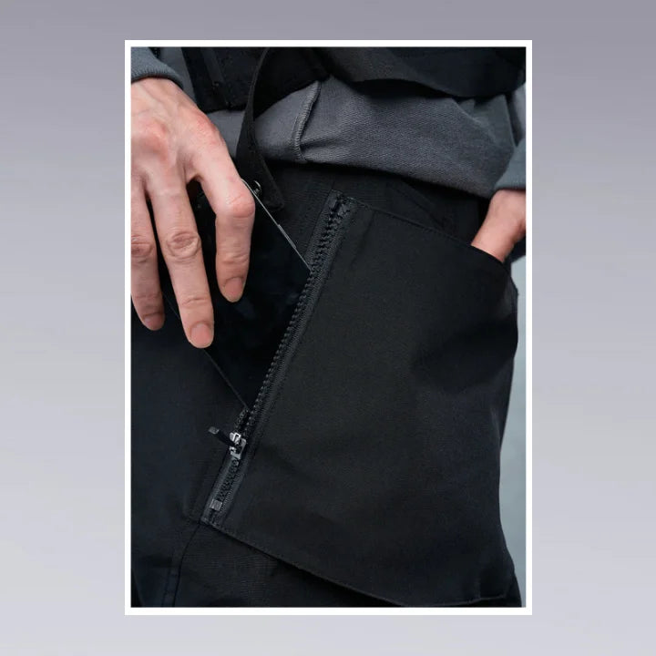 A man is putting his phone inside his techwear pants zipper pocket.