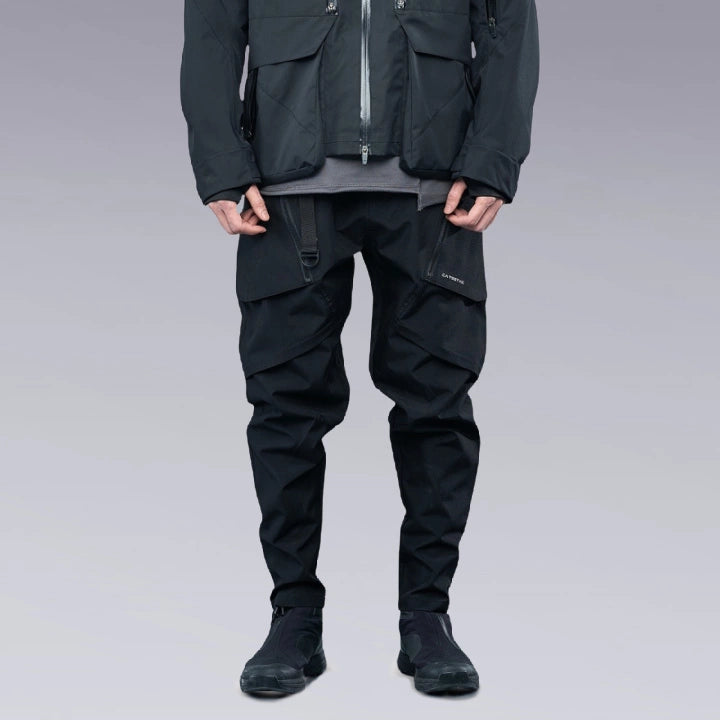 A man is wearing Techwear pants and putting his hands out of his pockets.